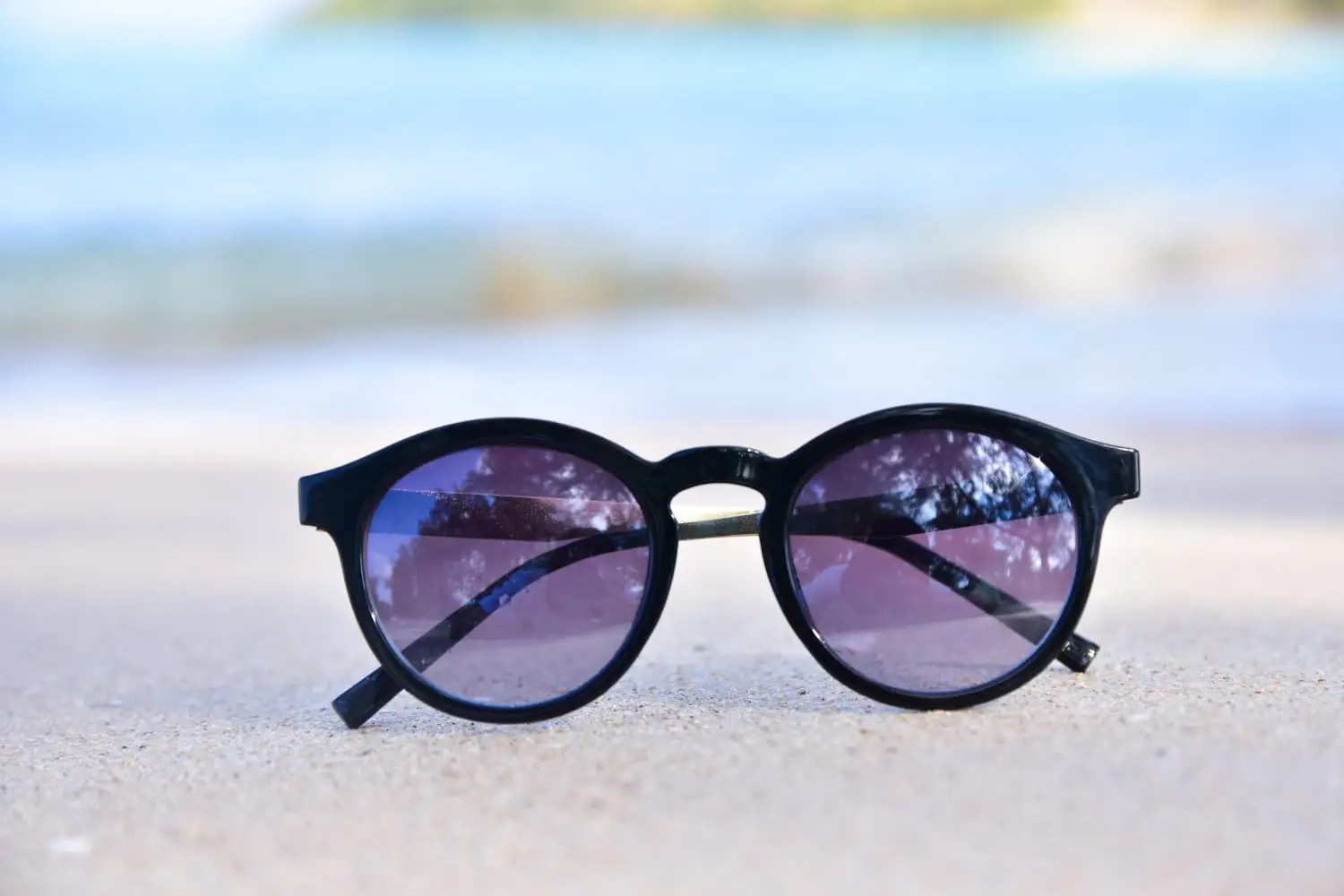 Black cat‑eye sunglasses with purple lenses.